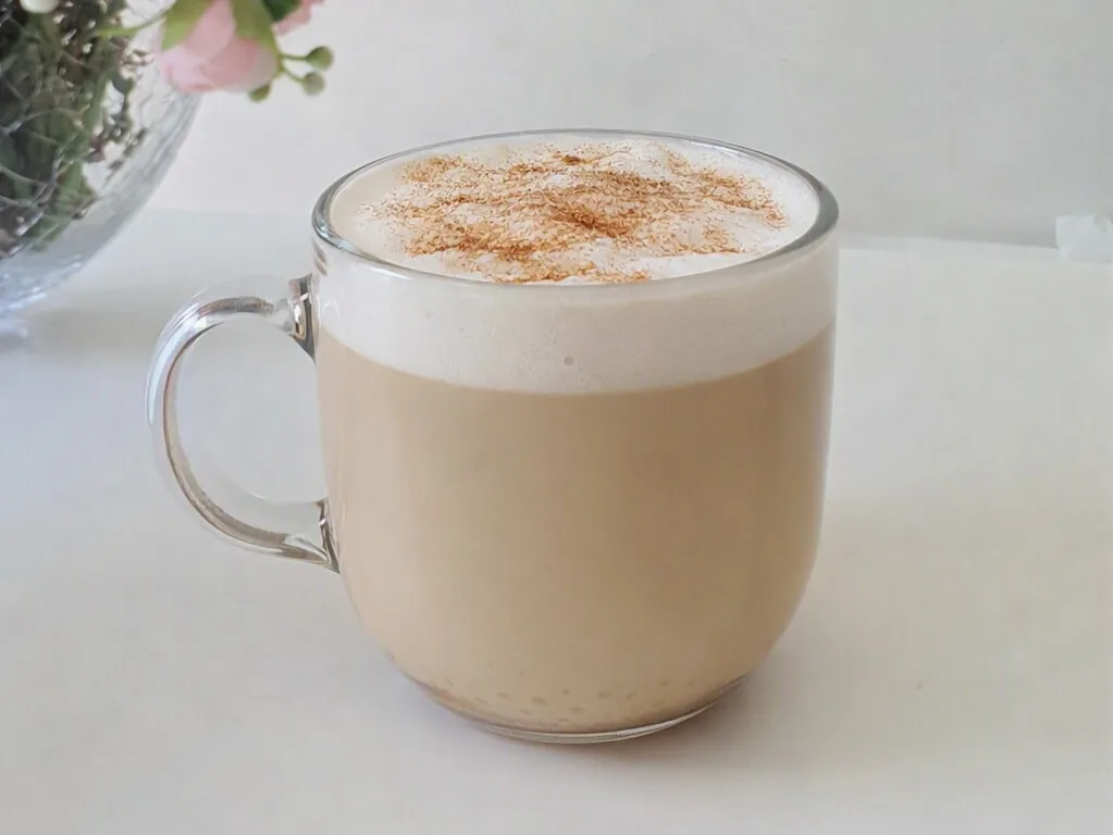 Café capuchino, en taza elegante con flores de fondo